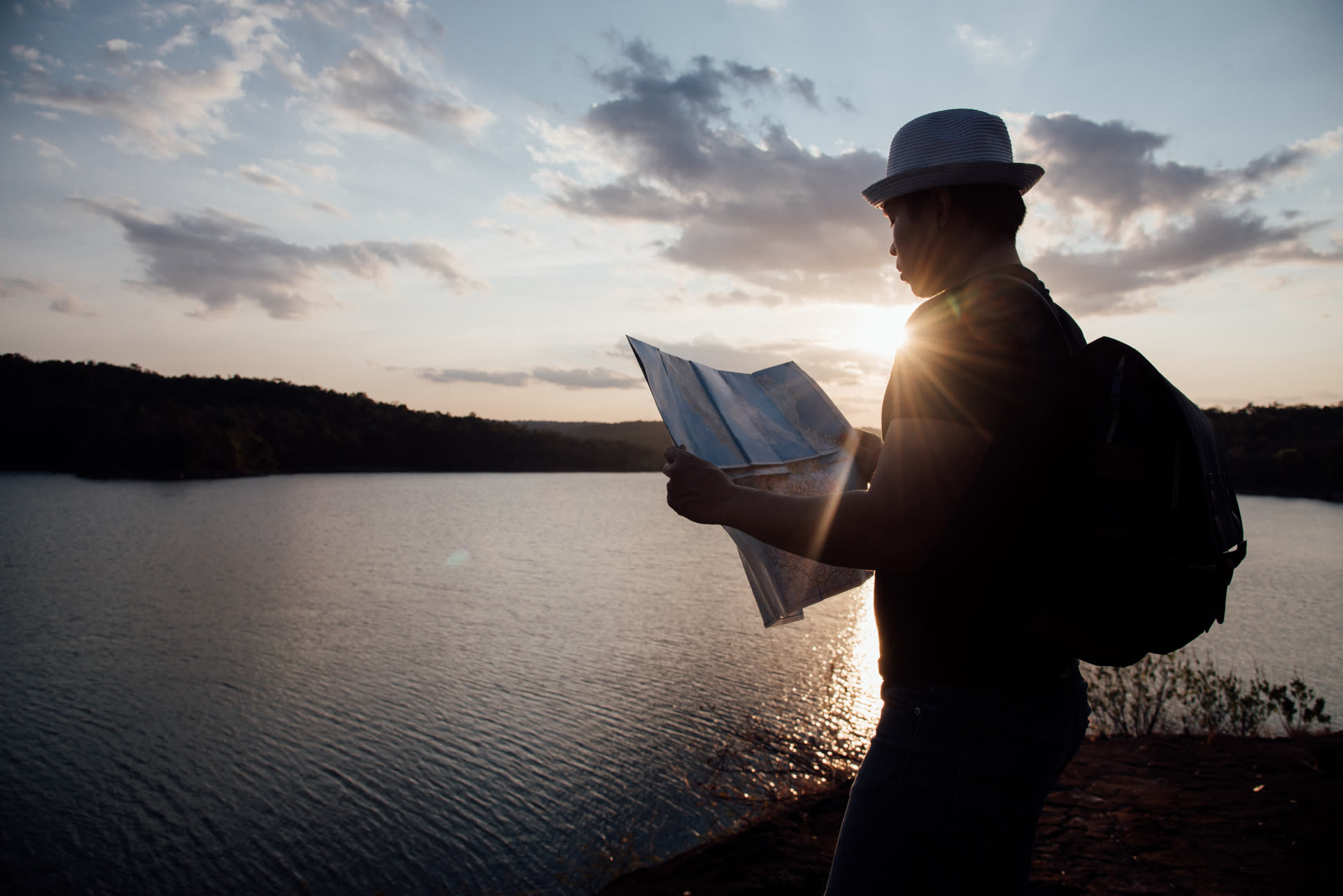 Pessoa observando um mapa ao entardecer, à procura de direção.